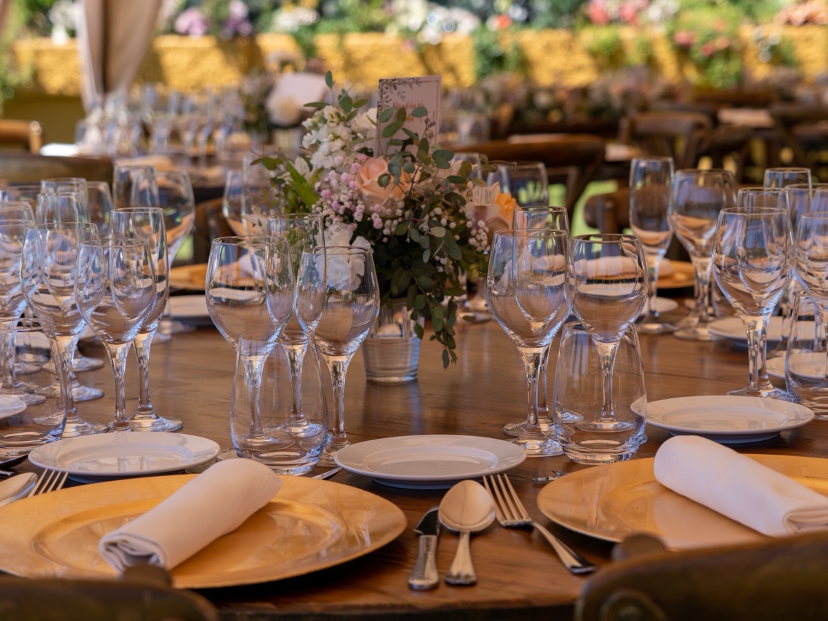 Gala dinner with round tables, charger plates and a lit stage behind