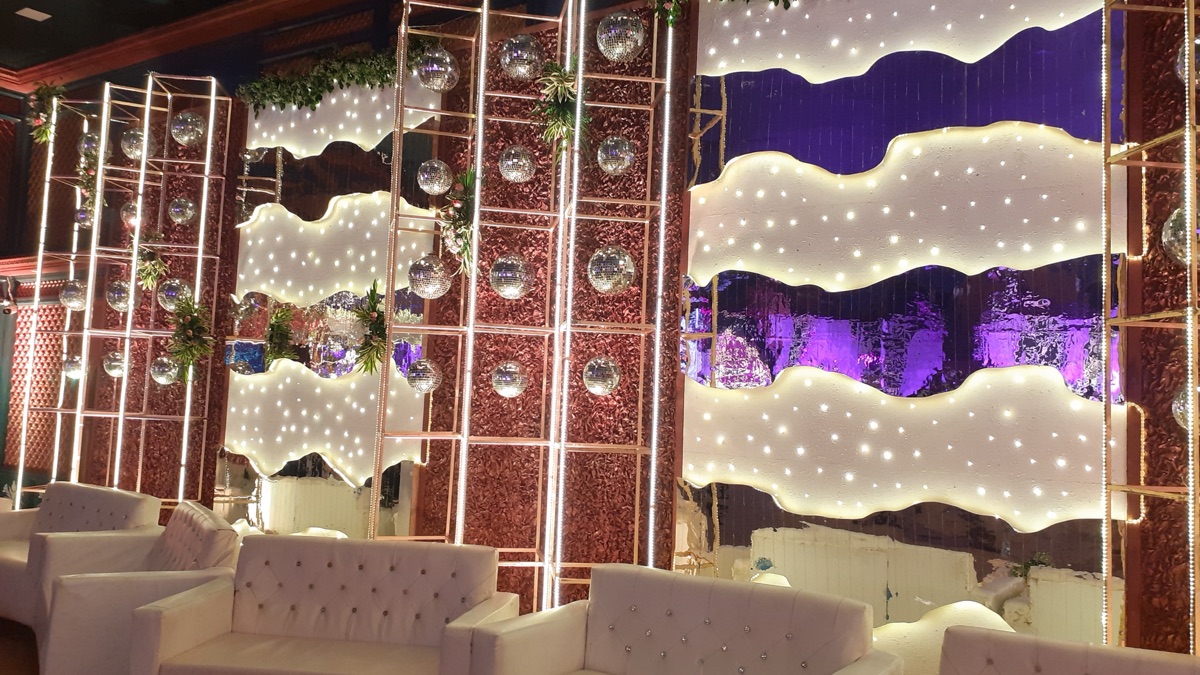 Reception event planners in Hyderabad: couple on a lit reception stage with LED backdrop and guests at tables
