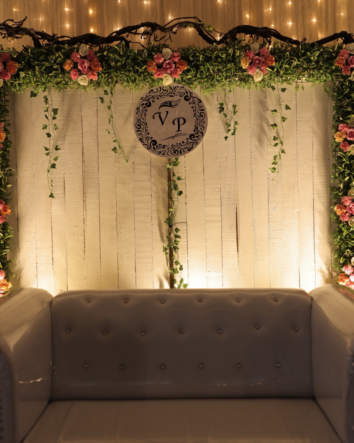 Couple on a reception stage with a sofa and LED backdrop wall in a banquet hall
