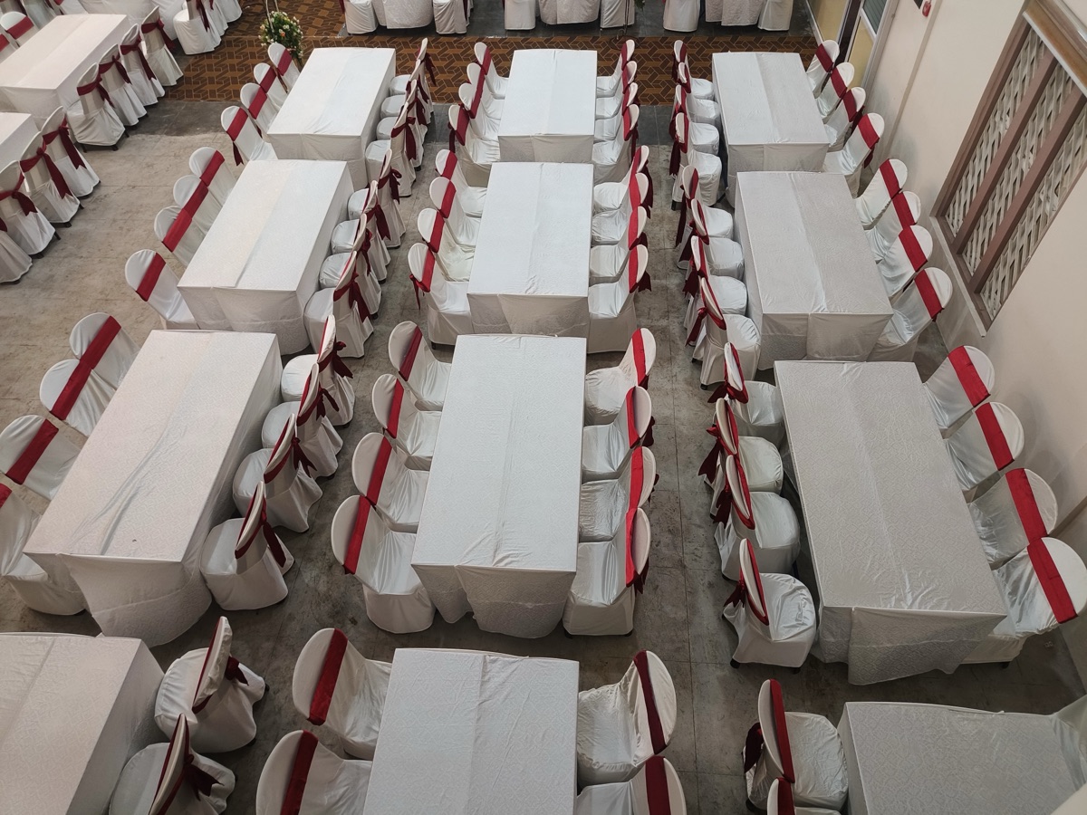 Walima lunch with long family tables and matching chairs in a decorated hall