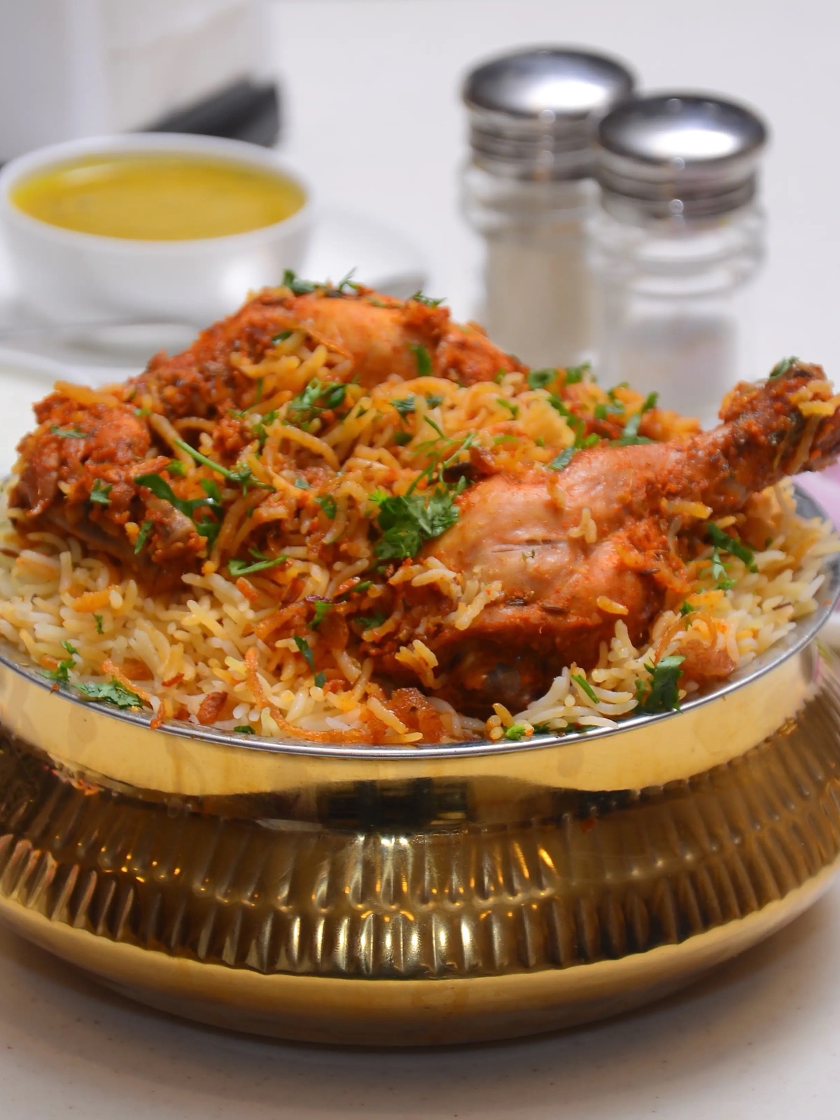 Sealed dum biryani handi being opened by a cook, steam rising from the rice