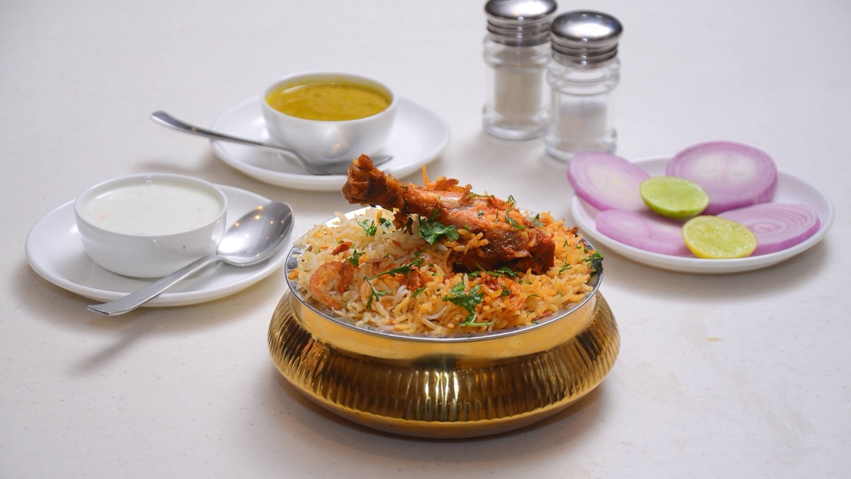 Long wedding buffet in Hyderabad with steaming dum biryani, mutton curry and tandoori kebabs in brass chafing dishes, framed by marigold garlands