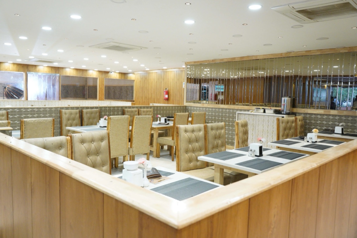 Dining hall of Mubarak Restaurant in Medchal with family seating and an open tandoor counter at the back